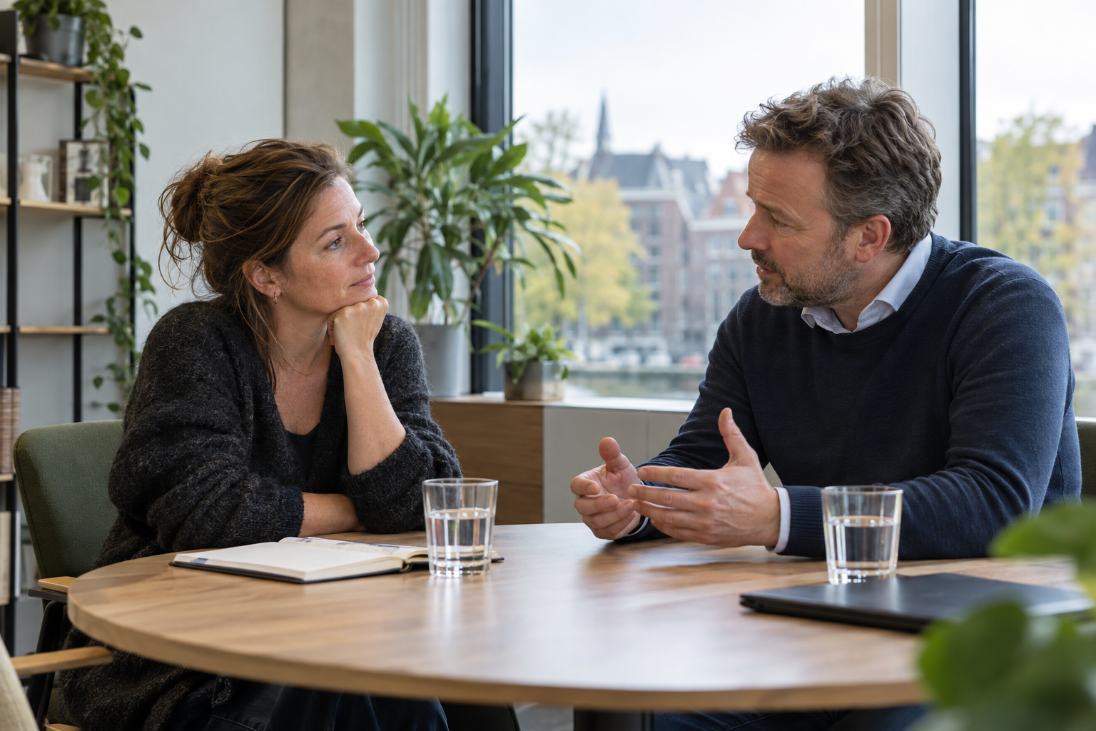 Two people having an open conversation across a table in an office